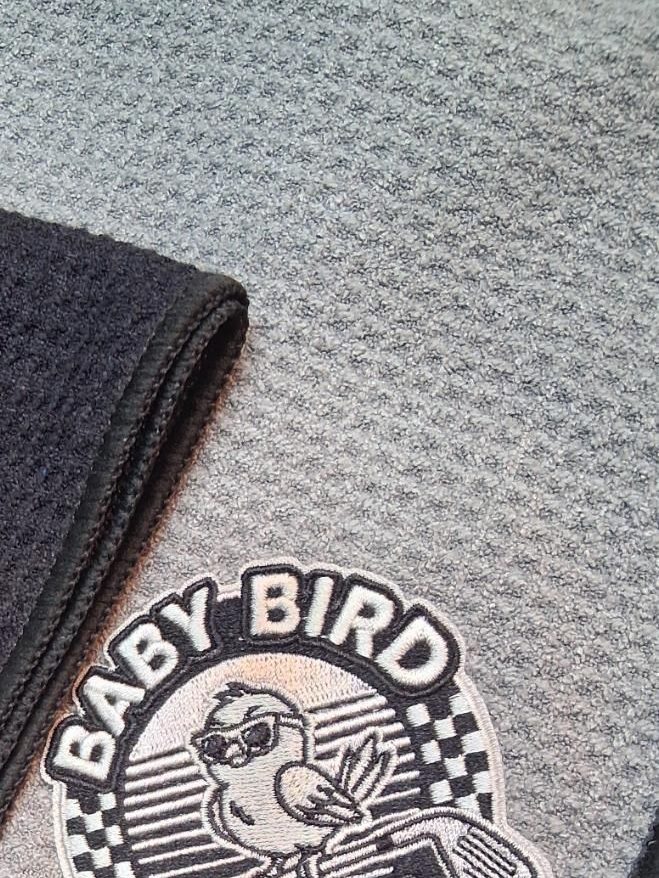 A gray waffle golf towel with a gray Baby Bird Grips patch
